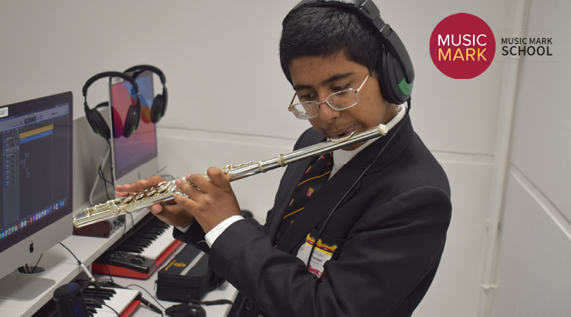 Student plays the flute, wearing a pair of headphones.