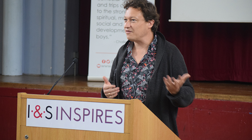 A man speaks at a lectern with 'I&S Inspires' signage on the front.